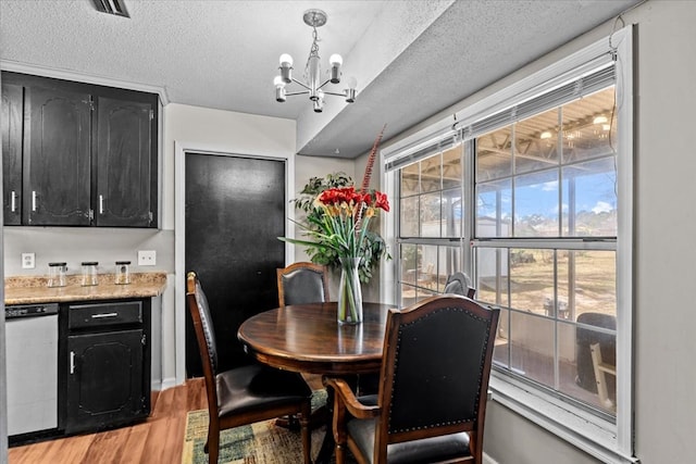 dining space featuring a chandelier, light wood finished floors, and a textured ceiling