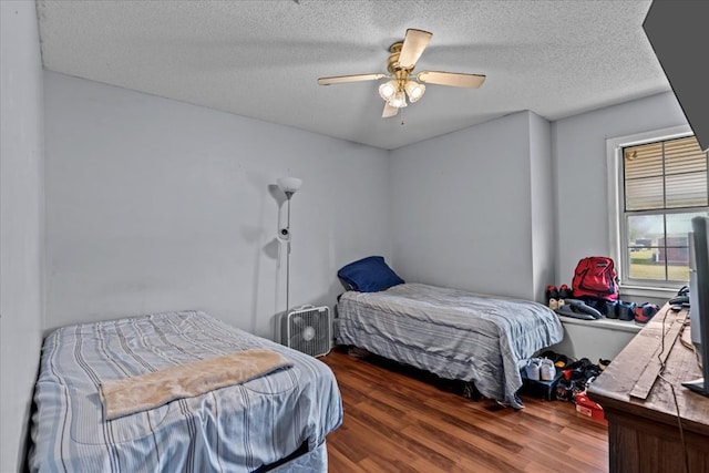 bedroom with ceiling fan, a textured ceiling, and wood finished floors