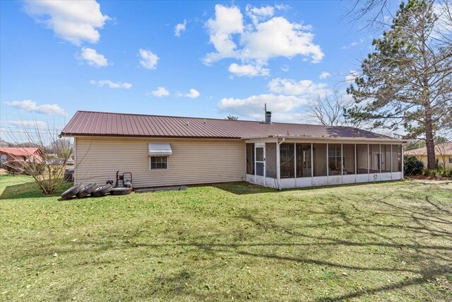 rear view of house with a sunroom, a yard, and metal roof