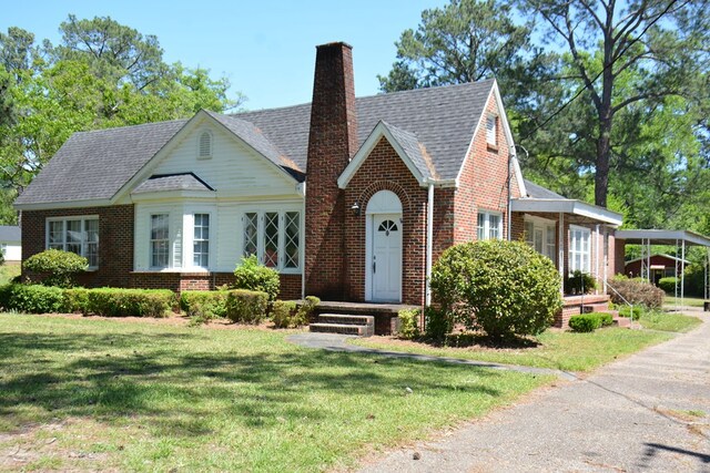 790 Claxton Ave, Elba, AL 36323 - tudor house featuring a chimney, brick siding, roof with shingles, and a front yard