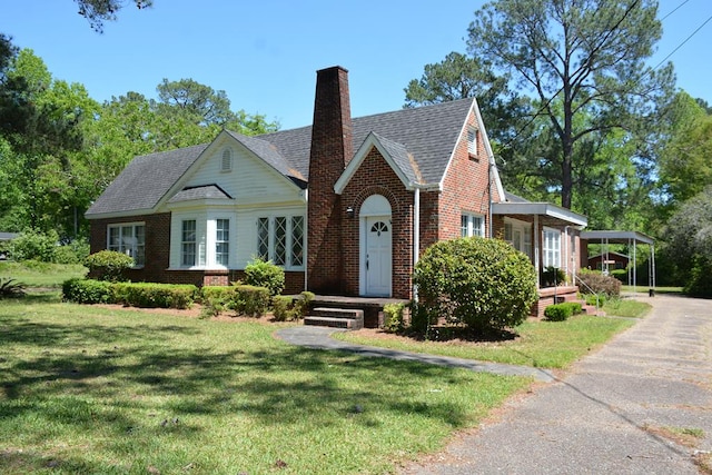 790 Claxton Ave, Elba, AL 36323 - tudor home featuring brick siding, a chimney, a front yard, and a carport