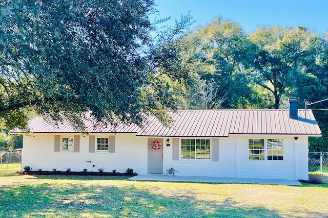 ranch-style home featuring metal roof and a front yard