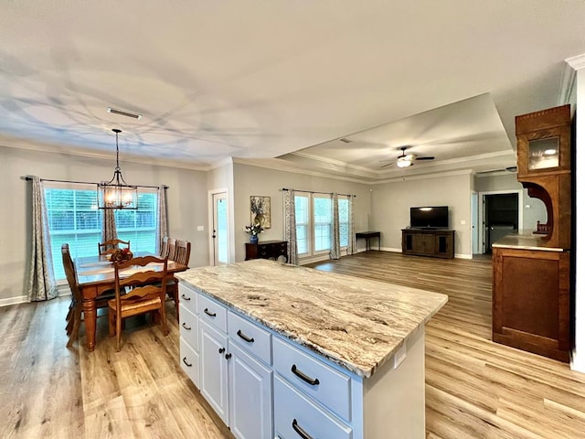 kitchen featuring a center island, white cabinets, hanging light fixtures, light hardwood / wood-style flooring, and ornamental molding