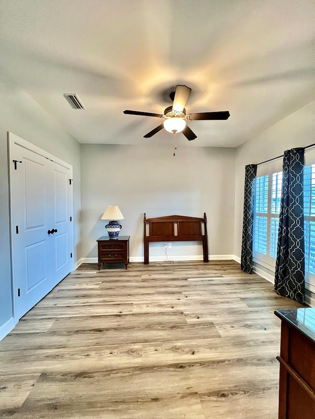 unfurnished bedroom featuring ceiling fan, a closet, and light wood-type flooring