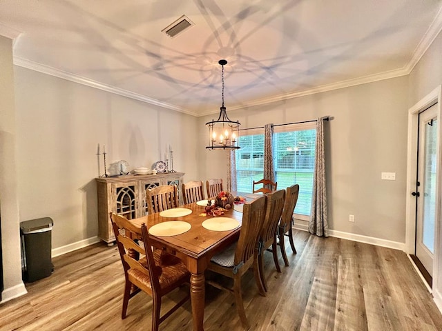 dining space with hardwood / wood-style floors, an inviting chandelier, and ornamental molding