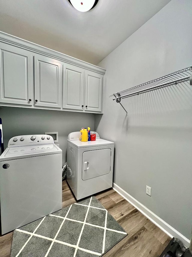 laundry area featuring separate washer and dryer, dark hardwood / wood-style flooring, and cabinets