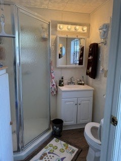 bathroom with vanity, a shower with door, and toilet