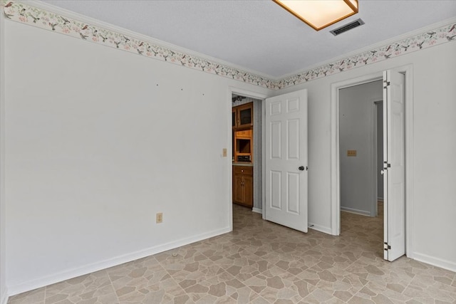 unfurnished room with a textured ceiling and ornamental molding