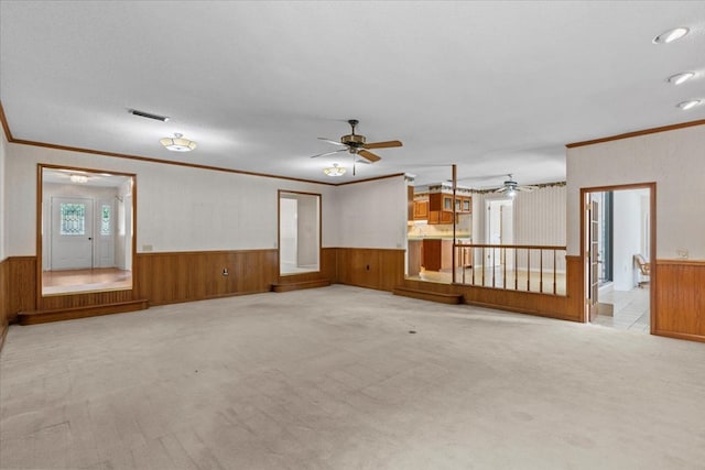 carpeted spare room with wood walls, ceiling fan, a textured ceiling, and ornamental molding