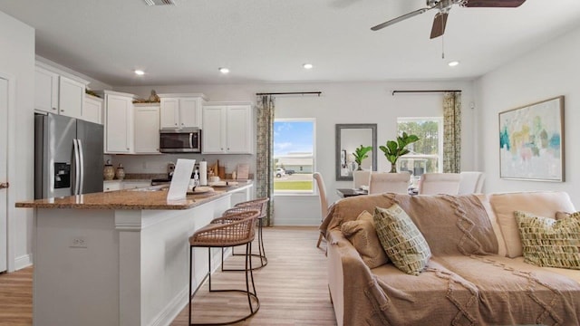 267 Fawnfield Ln, Dothan, AL 36301 - kitchen featuring stainless steel appliances, light wood-style flooring, white cabinets, a kitchen breakfast bar, and stone countertops