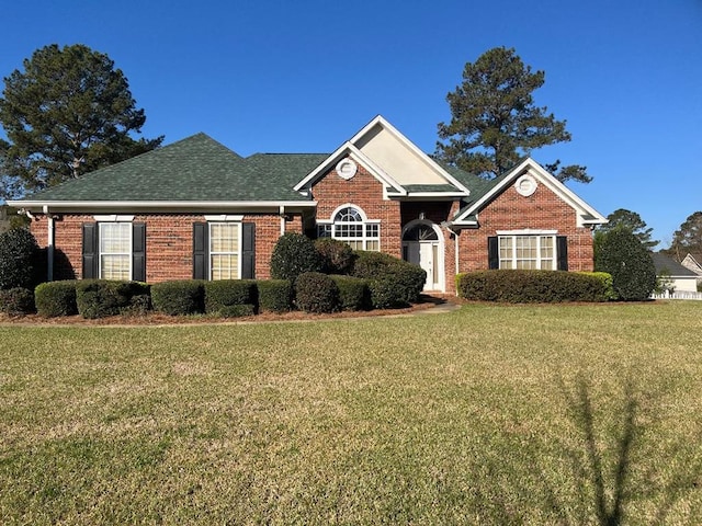 view of front of home featuring brick siding, a front lawn, and a shingled roof