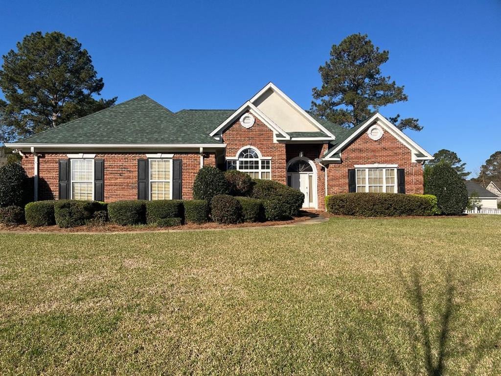 view of front of property featuring brick siding and a front lawn