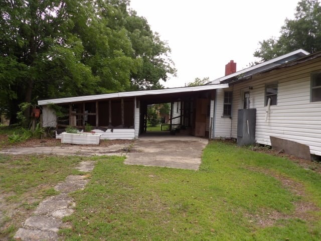 rear view of property featuring a yard and a carport