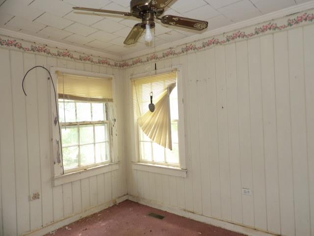 unfurnished room with ceiling fan, wooden walls, and ornamental molding