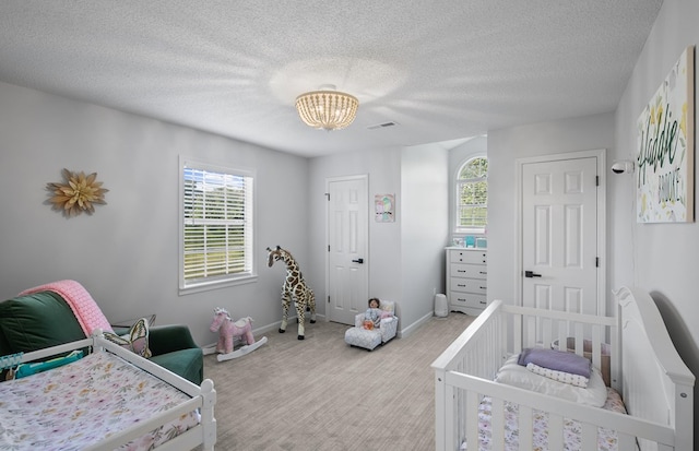 856 S County Rd 49, Dothan, AL 36301 - bedroom with multiple windows, light colored carpet, a textured ceiling, a crib, and baseboards