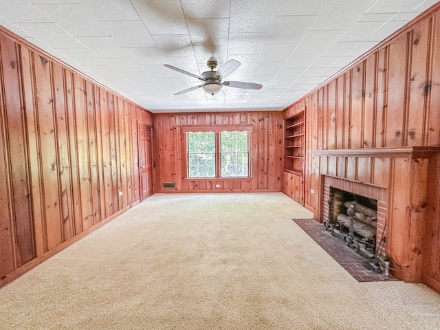 800 W Brookside Ave, Geneva, AL 36340 - unfurnished living room with built in shelves, wood walls, a fireplace, carpet floors, and a ceiling fan