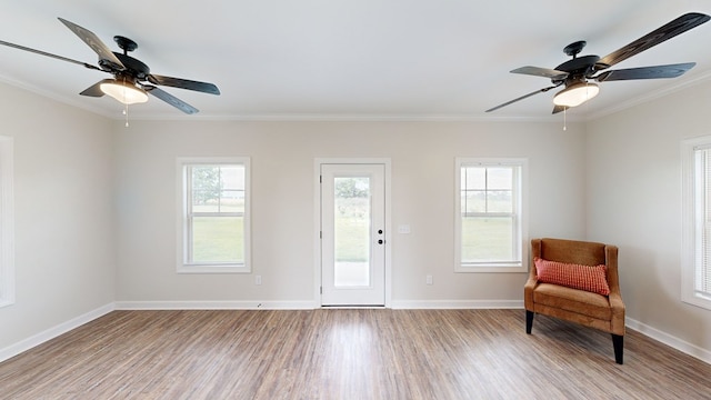 living area with ceiling fan, light hardwood / wood-style floors, crown molding, and a wealth of natural light