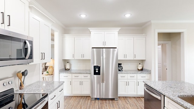 kitchen with light stone counters, white cabinetry, stainless steel appliances, and ornamental molding