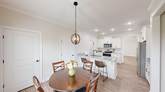 dining area with crown molding, sink, and light hardwood / wood-style floors