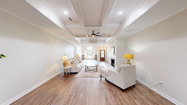 living room featuring coffered ceiling, hardwood / wood-style flooring, ceiling fan, ornamental molding, and beamed ceiling