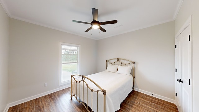 bedroom with ceiling fan, dark hardwood / wood-style floors, crown molding, and a closet