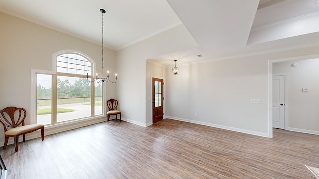 empty room with a chandelier, wood-type flooring, and crown molding