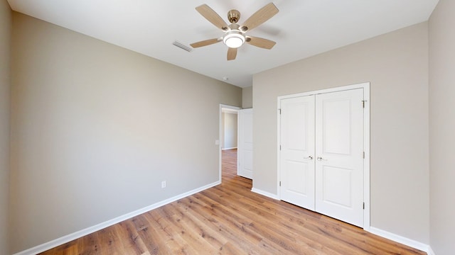 unfurnished bedroom with a closet, light wood finished floors, visible vents, and baseboards