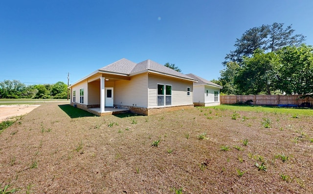 rear view of house featuring a patio area, fence, a yard, and roof with shingles