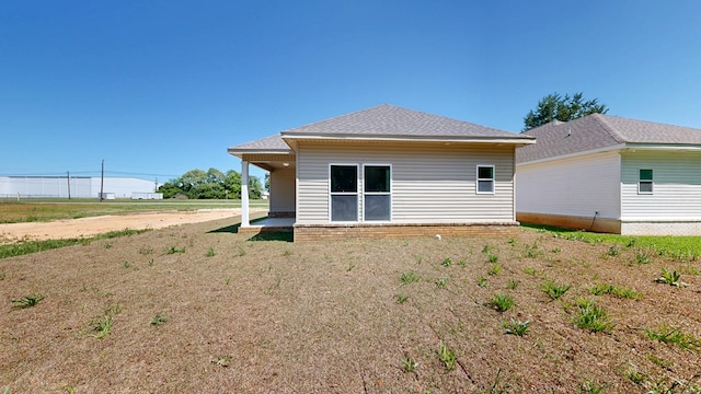 rear view of house featuring roof with shingles