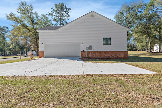 view of side of home with a garage, driveway, a yard, and brick siding