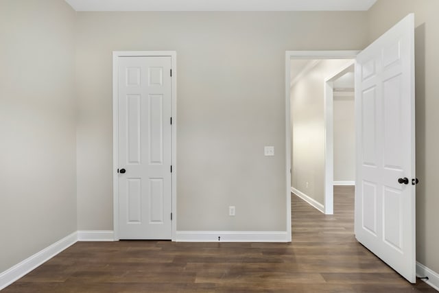 unfurnished bedroom with dark wood-type flooring and baseboards