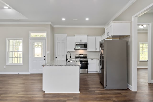 kitchen with stainless steel appliances, white cabinets, a kitchen island with sink, a sink, and light stone countertops