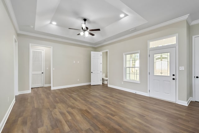 interior space with dark wood-type flooring, a raised ceiling, ornamental molding, and baseboards