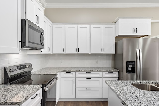 kitchen featuring light stone countertops, white cabinetry, appliances with stainless steel finishes, and crown molding