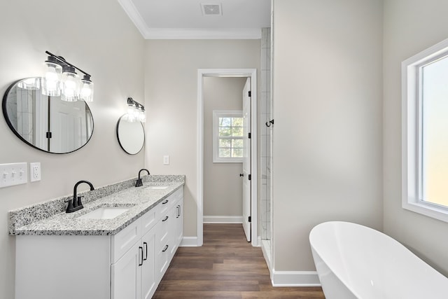 bathroom with ornamental molding, a freestanding tub, a sink, and visible vents