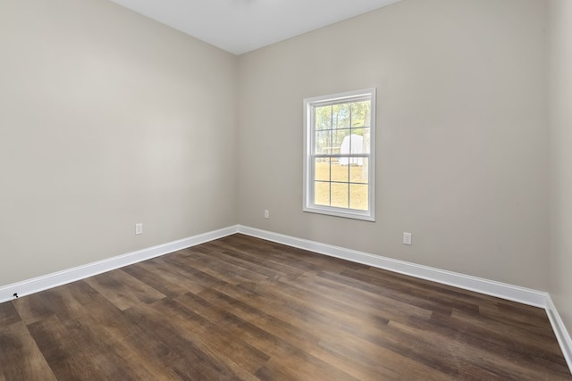 spare room featuring dark wood finished floors and baseboards