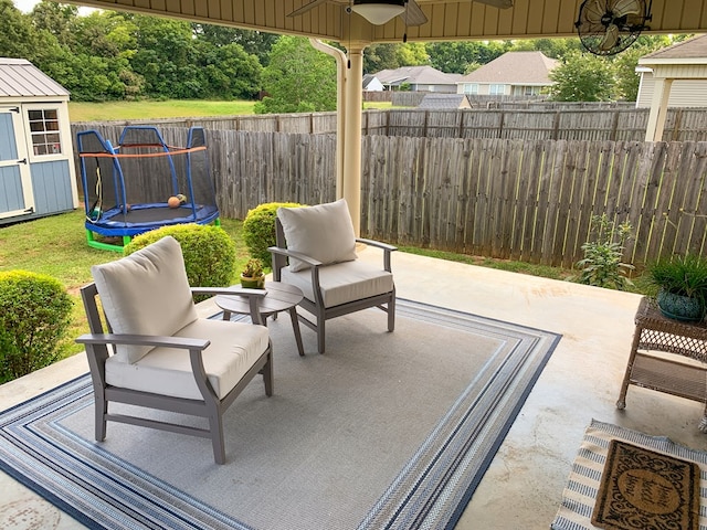 202 Moonlight Ln, Midland City, AL 36350 - fenced backyard featuring a trampoline, a ceiling fan, a storage unit, and a patio