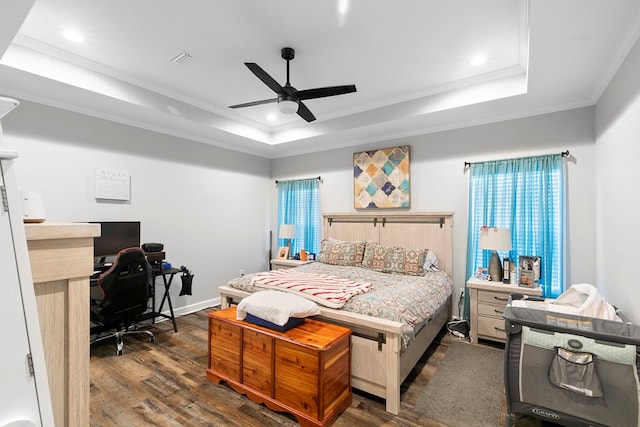 bedroom with ornamental molding, a tray ceiling, wood finished floors, and visible vents