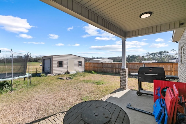 view of yard featuring a trampoline, a patio area, a fenced backyard, and an outdoor structure