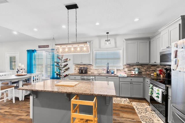 kitchen featuring tasteful backsplash, appliances with stainless steel finishes, dark wood-type flooring, gray cabinets, and a sink