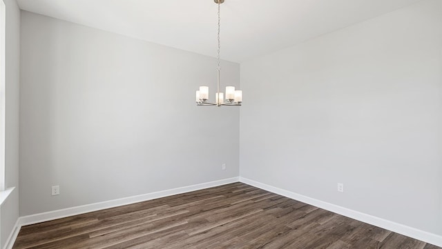 empty room featuring an inviting chandelier and dark wood-type flooring