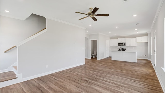 unfurnished living room featuring light hardwood / wood-style flooring, ceiling fan, and ornamental molding