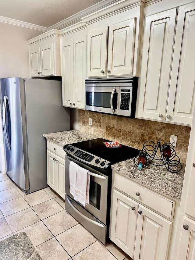 kitchen featuring stainless steel appliances, light stone countertops, ornamental molding, decorative backsplash, and light tile patterned flooring