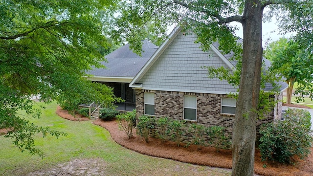 view of side of home with a sunroom and a lawn