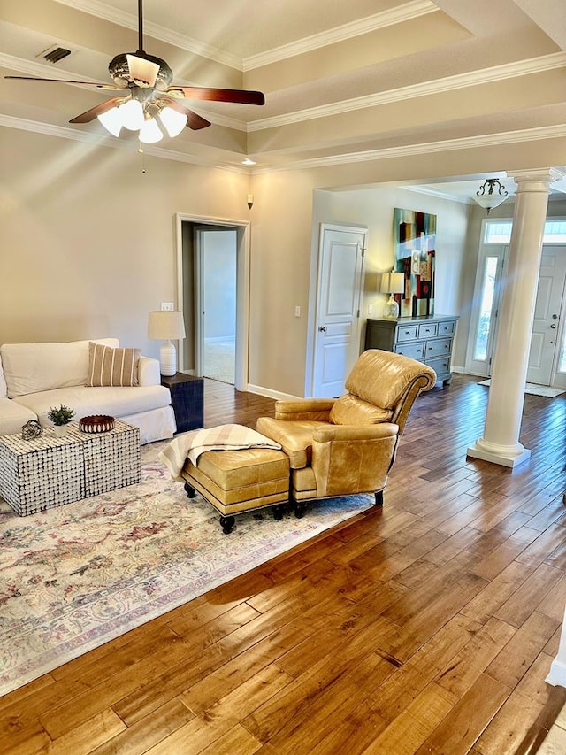 living room featuring ornate columns, a raised ceiling, ceiling fan, ornamental molding, and wood-type flooring