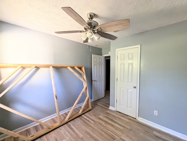 unfurnished bedroom with ceiling fan, hardwood / wood-style floors, and a textured ceiling