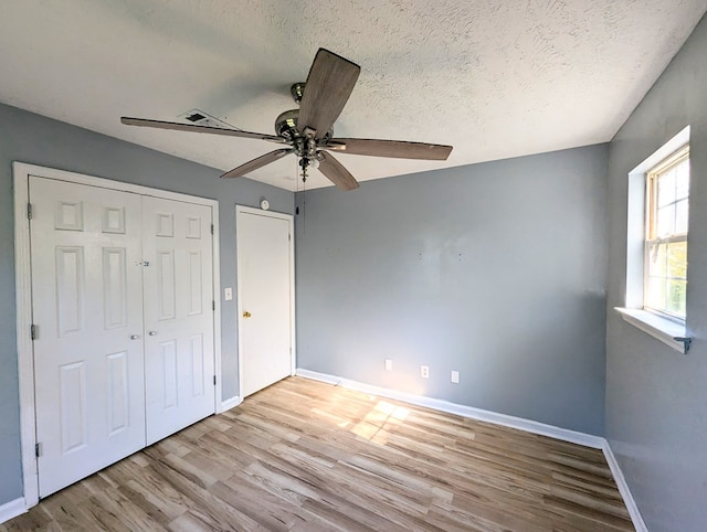 unfurnished bedroom featuring a textured ceiling, light wood-type flooring, and ceiling fan