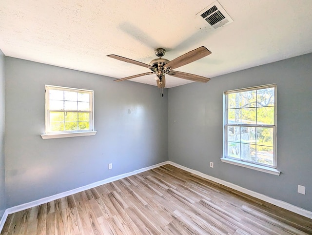 spare room with a textured ceiling, light hardwood / wood-style floors, plenty of natural light, and ceiling fan