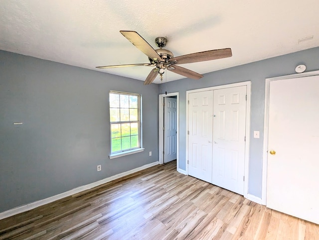 unfurnished bedroom with ceiling fan, light wood-type flooring, and a textured ceiling