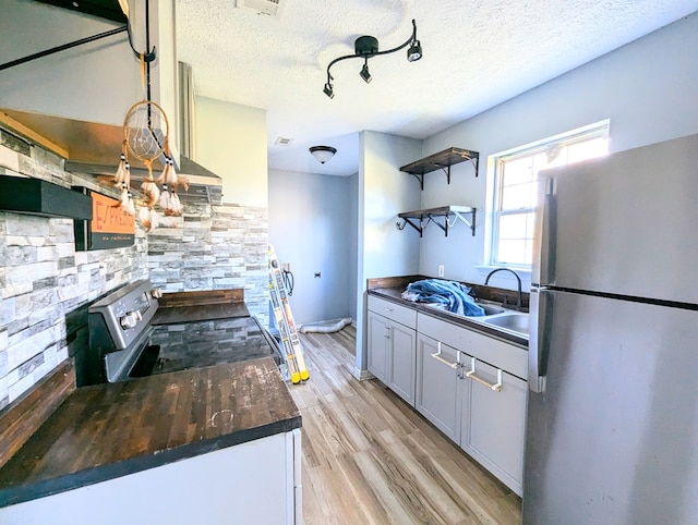 kitchen with a textured ceiling, light hardwood / wood-style floors, sink, and stainless steel appliances